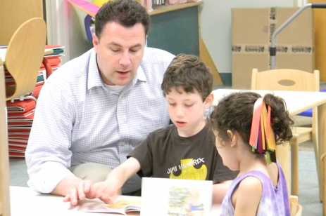 Father reading with his children at The Fatherhood Project Dads in Schools event